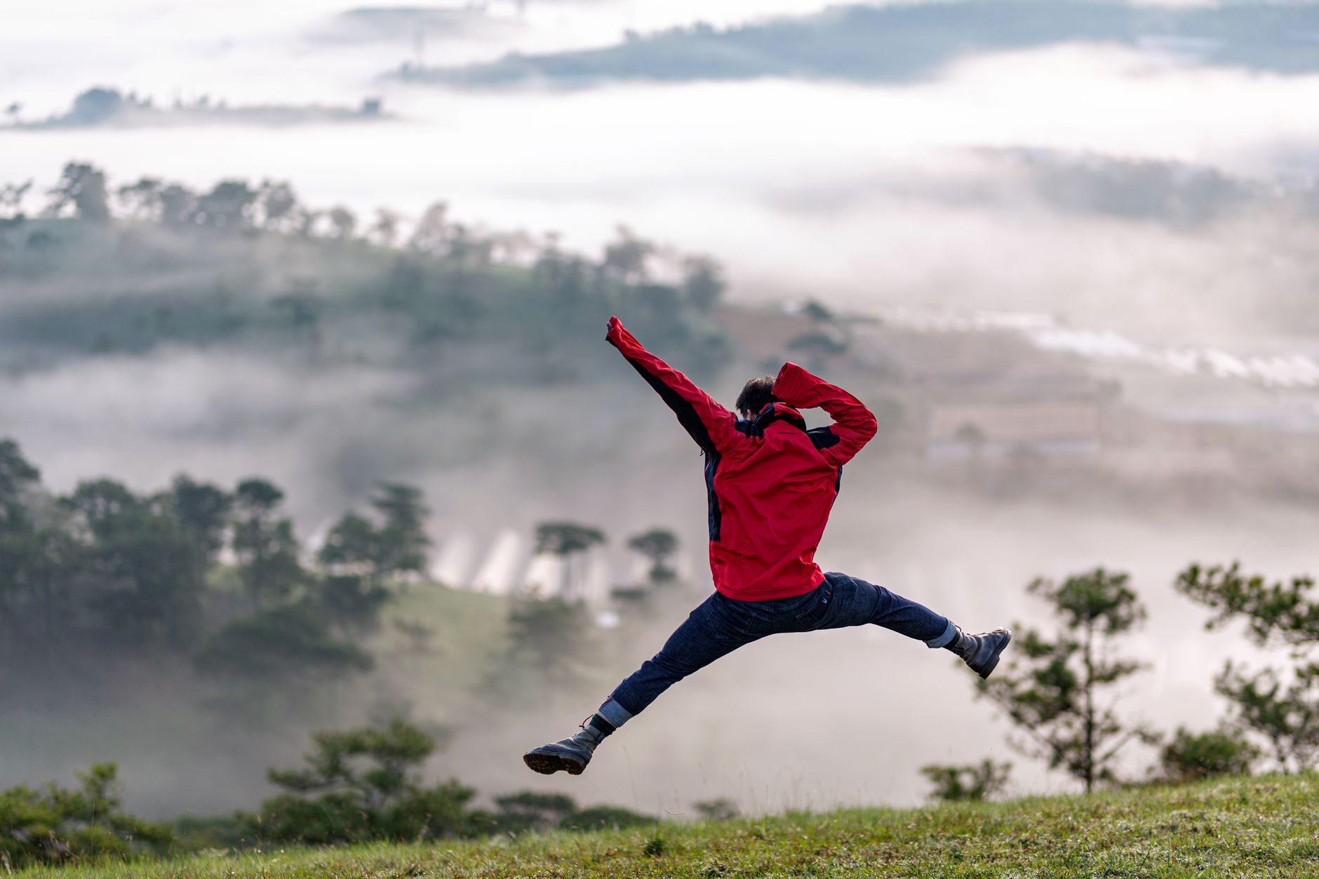 young man jumping on green hill